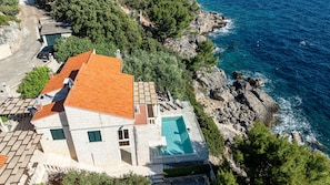 Ein Küstenhaus mit Pool, Steinstufen und Meerblick.