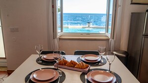 A dining table set for four with plates, glasses, and a croissant tray, overlooking a pool and ocean view. - Villa Toma by Villas Guide (Orebic)