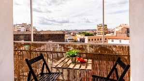 Un balcón con una mesa y sillas, una planta en maceta y vista a la ciudad.