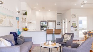 Un salon moderne avec un canapé gris, une table basse ronde et un coin repas avec une table dressée pour deux personnes.