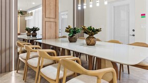 Zona pranzo moderna con un tavolo lungo, diverse sedie e piante decorative.