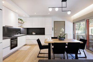 Una cucina moderna con mobili bianchi, un piano di lavoro nero e un tavolo da pranzo in legno con quattro sedie.