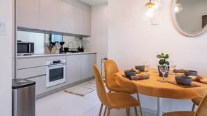 Eine moderne Küche mit weißen Schränken, einer Mikrowelle, einem Backofen und einem Essbereich mit einer gelben Tischdecke und Stühlen.