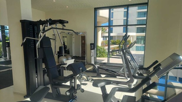 Ein Fitnessstudio mit unterschiedlichen Trainingsgeräten, großen Fenstern und Blick ins Freie.