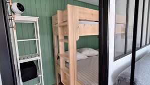 Kerrossänky, jossa on valkoinen tikapuu, valkoinen hyllykkö ja vihreä seinä.