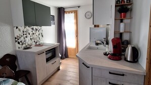 Pieni, käytännöllinen keittiö, jossa on mikroaaltouuni, kahvinkeitin ja seinällä oleva kello.