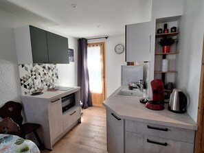 A compact kitchen with a microwave, coffee maker, and a clock on the wall. - Apartment for 4, 1 bed with washer in Samoëns (Samoëns)