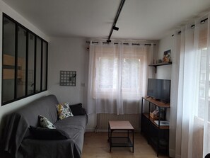 A living room with a grey sofa, a small table, a TV, and a radiator. - Apartment for 4, 1 bed with washer in Samoëns (Samoëns)