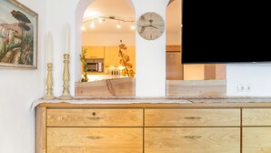 A modern kitchen with wooden cabinetry, a clock, and a flat-screen TV. - Apartment "Paula" with Mountain View, Private Terrace and Wi-Fi (Leutasch)