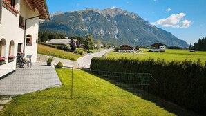 A building with a patio, a mountain view, and a road leading to other buildings. - Apartment "Paula" with Mountain View, Private Terrace and Wi-Fi (Leutasch)
