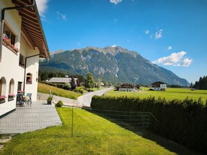 Ein Gebäude mit Terrasse, Blick auf die Berge und einer Straße, die zu anderen Gebäuden führt.