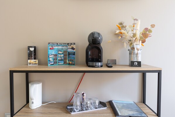 A wooden table with a coffee maker, a remote control, a vase with dried plants, and a framed picture. - Room 'Lotu' with Mountain View, Wi-Fi and Air Conditioning (Santa-Reparata-di-Balagna)