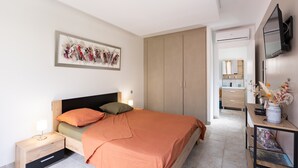 Un dormitorio con cama, mesita de noche, armario y televisor.