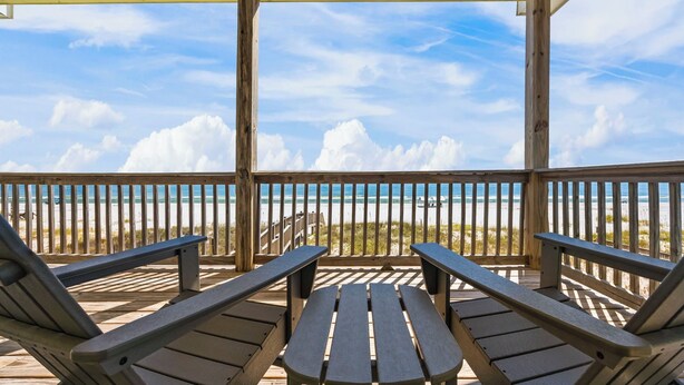 Una terraza de madera con bancos que da a una playa.