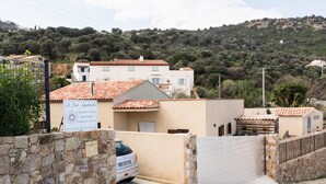 Un hotel con ingresso in pietra, un'auto parcheggiata davanti e vista su una collina con edifici.