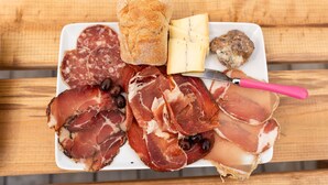Un piatto di salumi, formaggi e pane su un tavolo di legno.