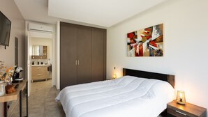 Una camera da letto con un letto, un comodino, opere d'arte a parete e vista sul bagno.