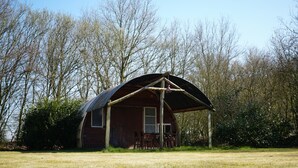 A rustic wooden barn with a large open porch and a covered area.