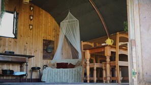 A cozy room with a wooden interior, a bed with a canopy, a table, and chairs. - Camping Ont Moeten - Romney Lodge (Rekken)