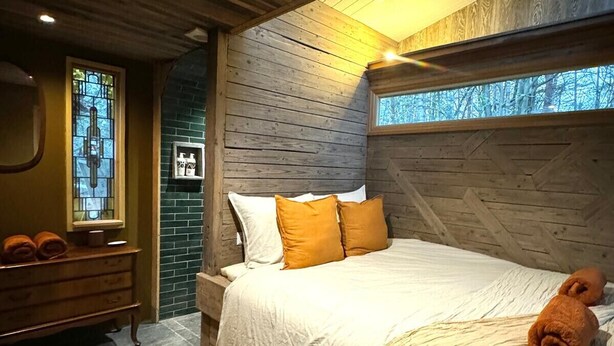 A wooden-paneled bedroom with a bed, a dresser, and a stained glass window. - Camping Ont Moeten - Hallertau (Rekken)