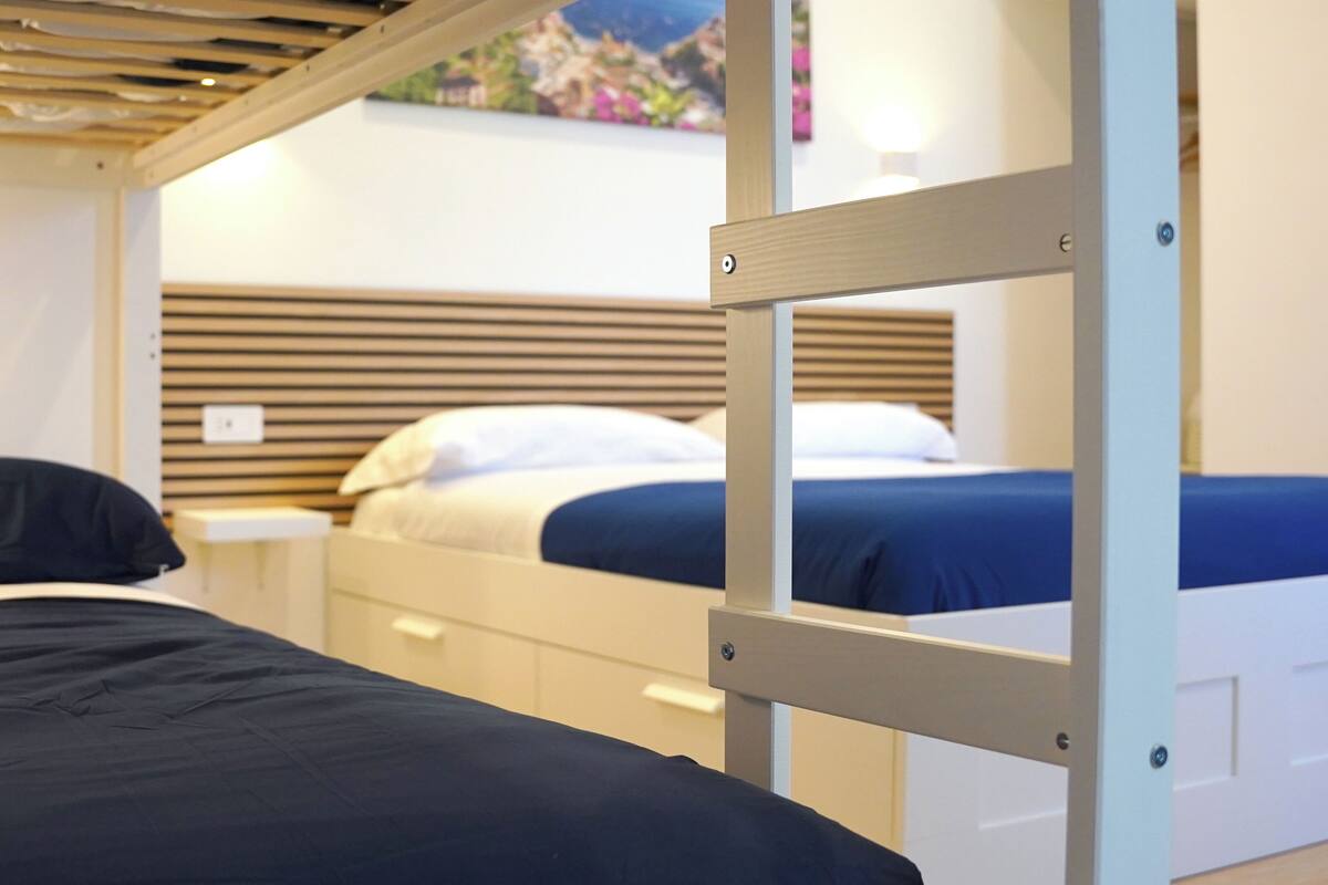 A bunk bed room with a wooden headboard, white nightstands, and a blue bedspread.