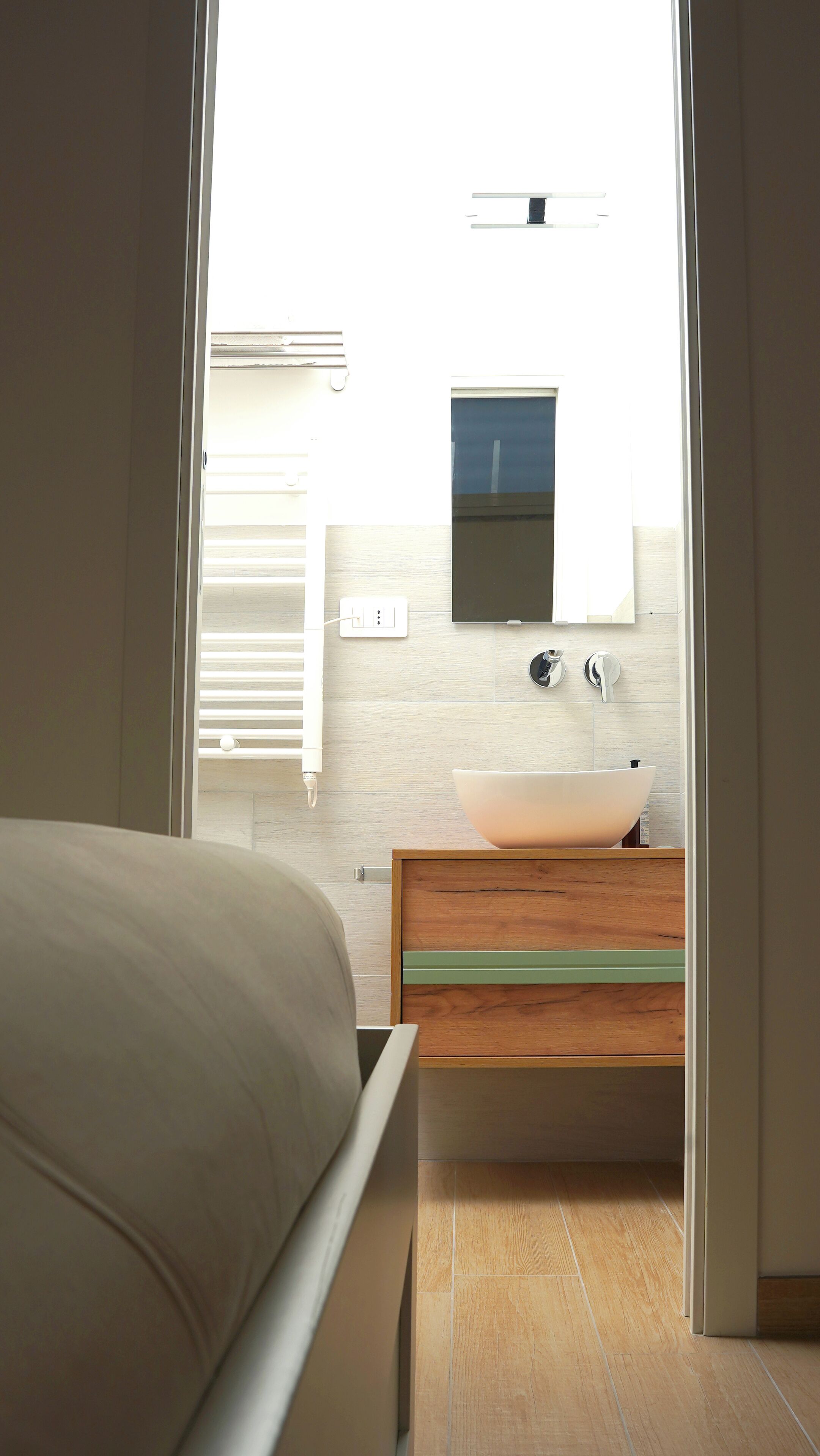 Une salle de bain moderne avec un grand lavabo blanc, un meuble-lavabo en bois et un miroir au-dessus du lavabo.