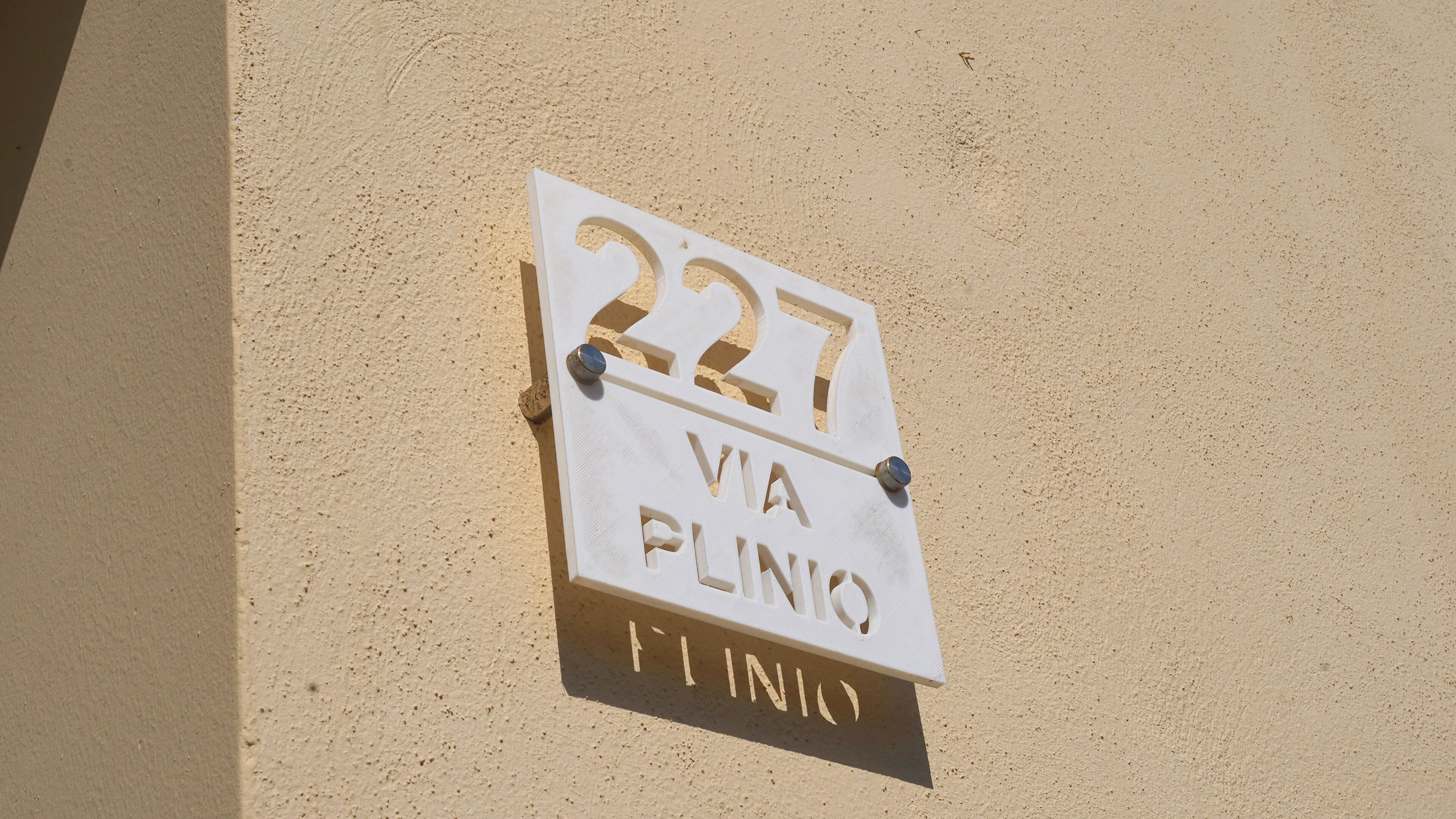 A building sign with the number 227 and the text "VIA PLINO".