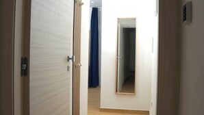 A hallway with a wooden door, a mirror, and a blue curtain. - Little Suites Pompeii (Torre Annunziata)