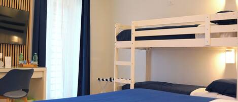 Habitación con literas, un escritorio, una silla, un televisor y una ventana con cortinas.