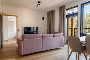 Un salon moderne comprenant un canapé, un téléviseur et un coin repas avec des chaises.