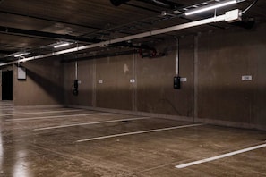 Eine Parkgarage mit Betonwänden und -böden, nummerierten Stellplätzen und Deckenbeleuchtung.
