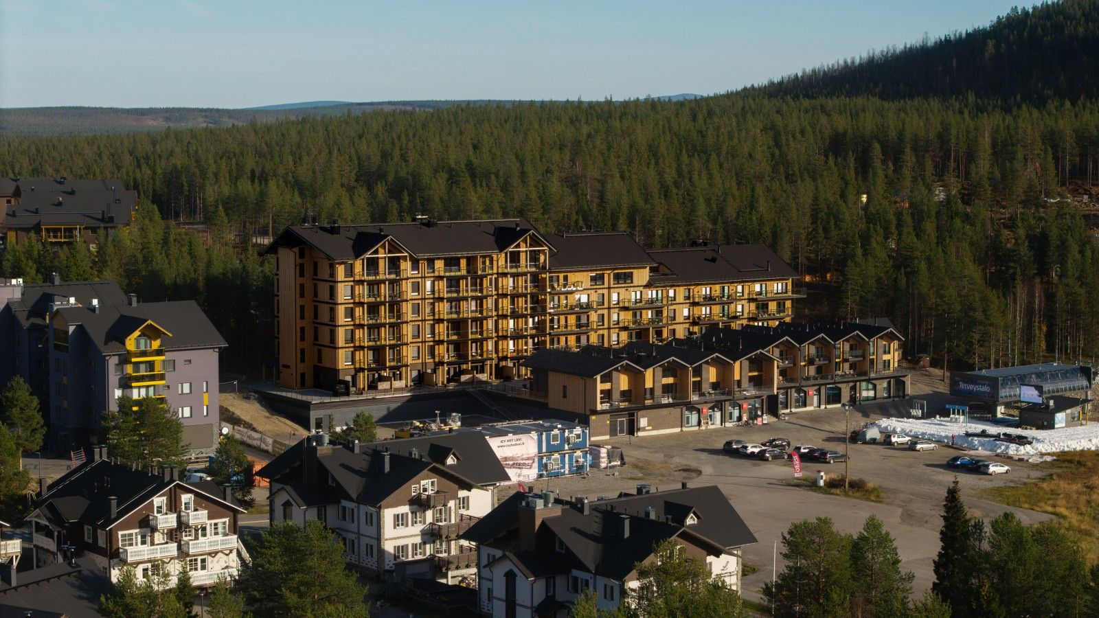A multi-story hotel with a central courtyard, surrounded by forested hills.