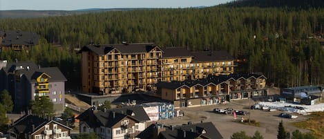A multi-story hotel with a central courtyard, surrounded by forested hills.