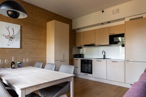 Eine moderne Küche mit Holzschränken, einem Esstisch mit Stühlen und einer Pendelleuchte.