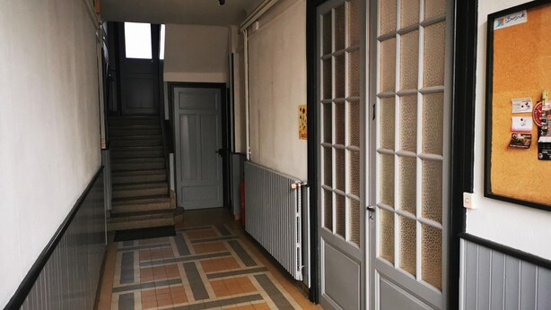 En hall med ett mönstrat golv, en trappa och en dörr med frostade glaspaneler.