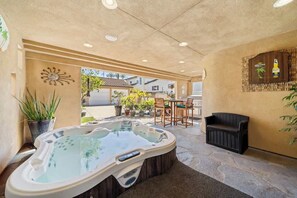 A hot tub area with a patio, seating, and a decorative wall. - Hot Tub Ocean Views 3 Bedroom Private Home (Carlsbad)