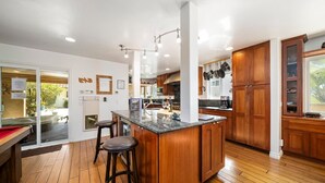 Een moderne keuken met houten kastjes, een centraal eiland met krukken en uitzicht op het buitengebied.