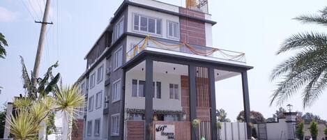 Un hôtel à plusieurs étages, doté d’une entrée couverte et d’une allée d’accès fermée par un portail.