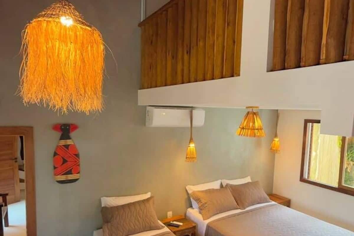 Una stanza con due letti, travi in legno e un lampadario.