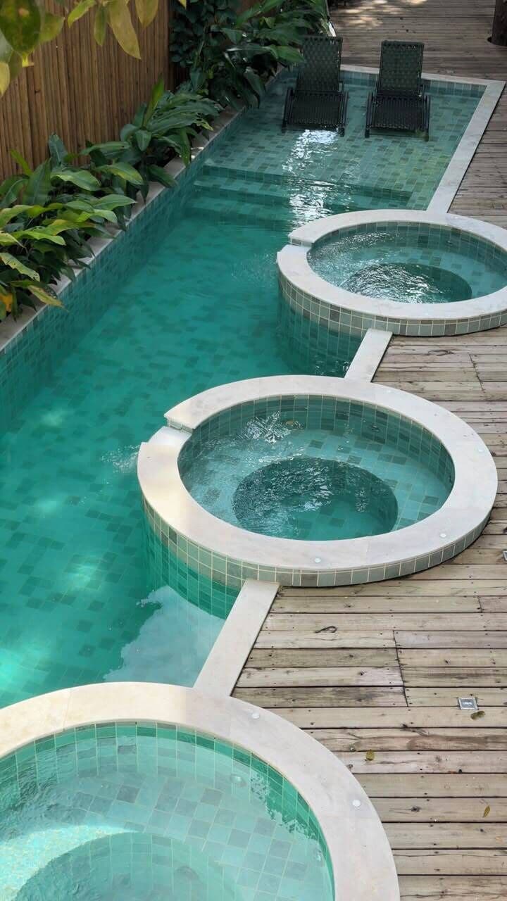 A pool area with three hot tubs and a wooden deck.