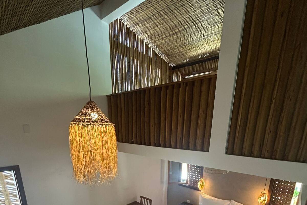 Un'ampia camera da letto con un letto grande, una lampada a sospensione e un piccolo angolo studio.