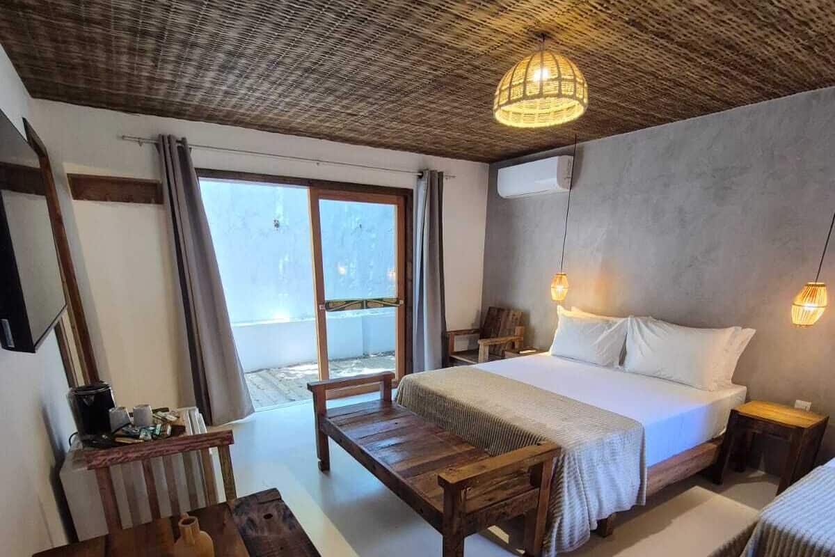 Una camera da letto con un letto grande, una panca di legno, un tavolino e un lampadario.