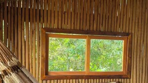 Una stanza con un letto, un'amaca e una finestra vista verde.