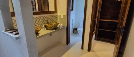 A modern bathroom with a large mirror, a sink with a decorative bowl, and a shower area.