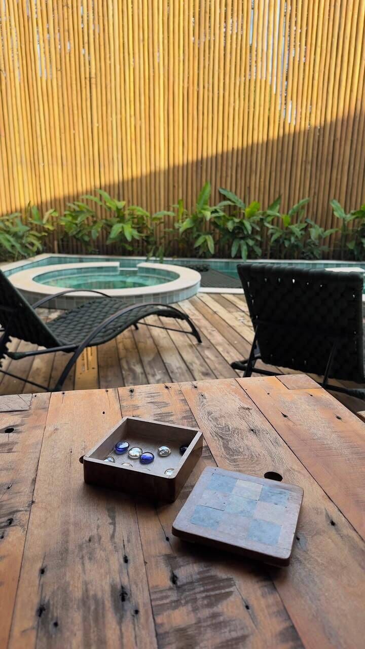 A wooden deck with a table, chairs, and a small pool.