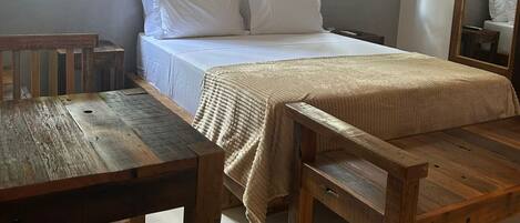 A bedroom with a bed, wooden furniture, and large windows.