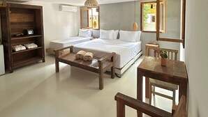 Una camera da letto con due letti, una panca in legno, un tavolino e un'ampia finestra.