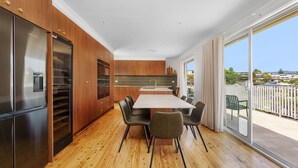 Une cuisine moderne avec des meubles en bois, un réfrigérateur en acier inoxydable et un coin repas comprenant une table et des chaises.
