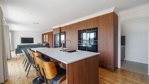 Une cuisine moderne dotée d’un îlot central, de meubles en bois et d’un coin repas avec des tabourets de bar.