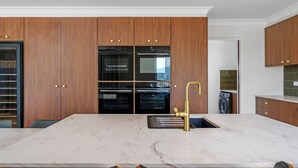 Une cuisine moderne avec des meubles en bois, un plan de travail en marbre et un robinet doré.